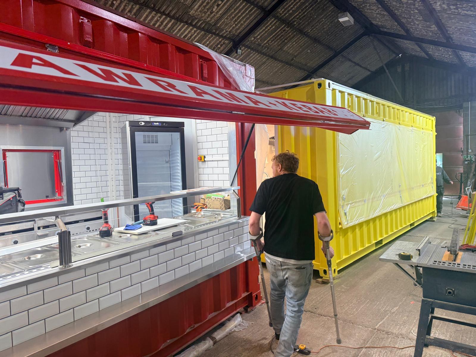 Converted shipping container with serving hatch open and stainless steel counter