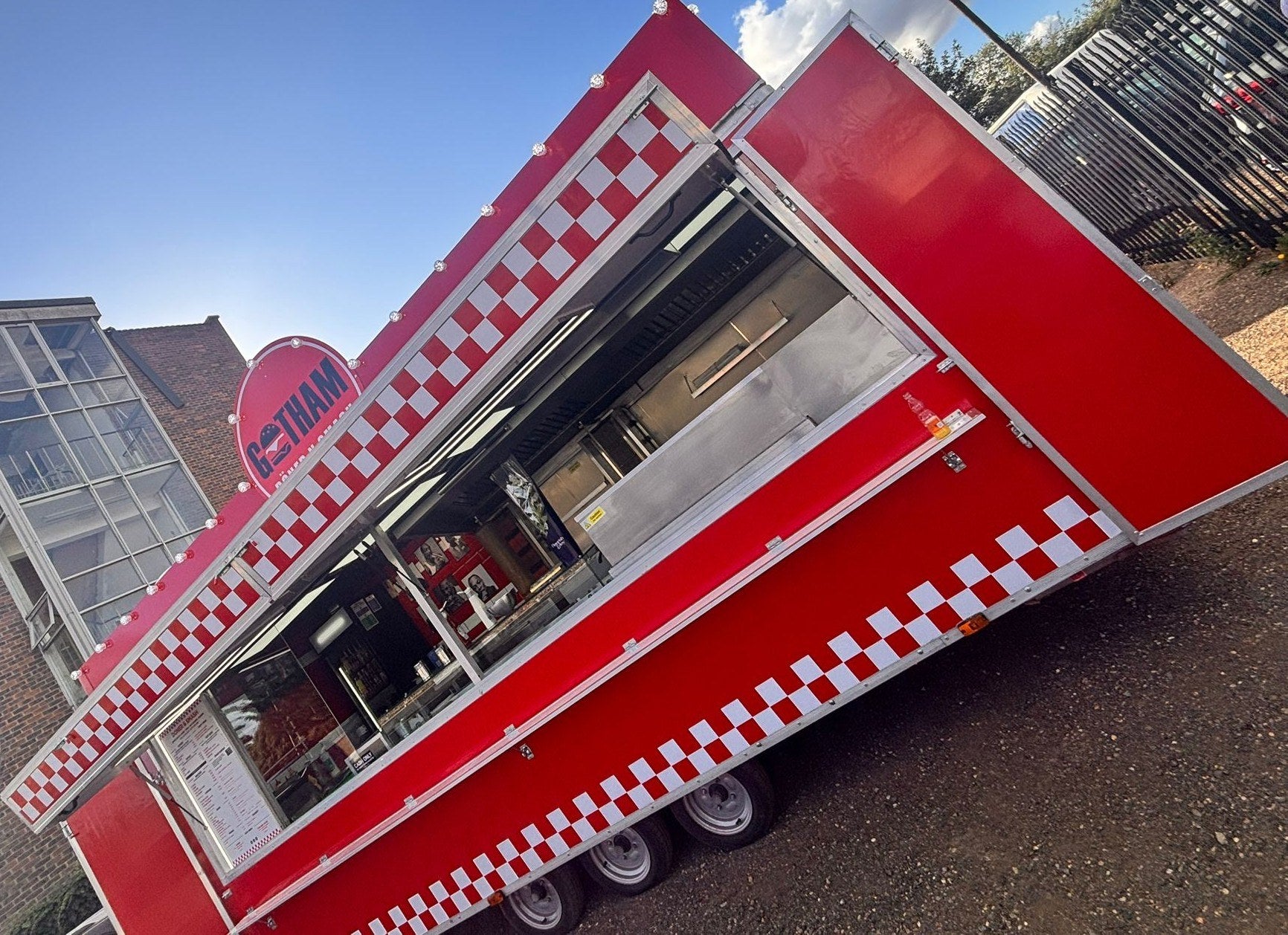 Red catering trailer with full-width serving hatch and multiple axles