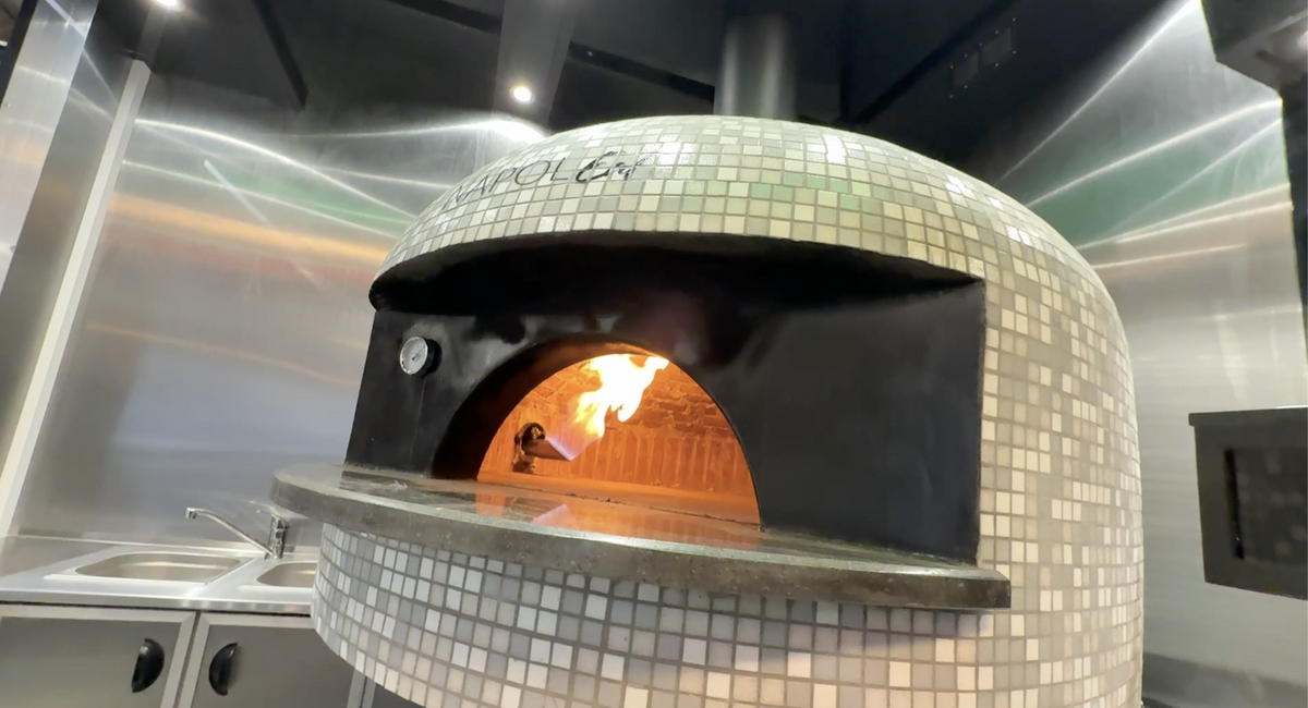 Oven with flames inside, tiled exterior, in a kitchen setting