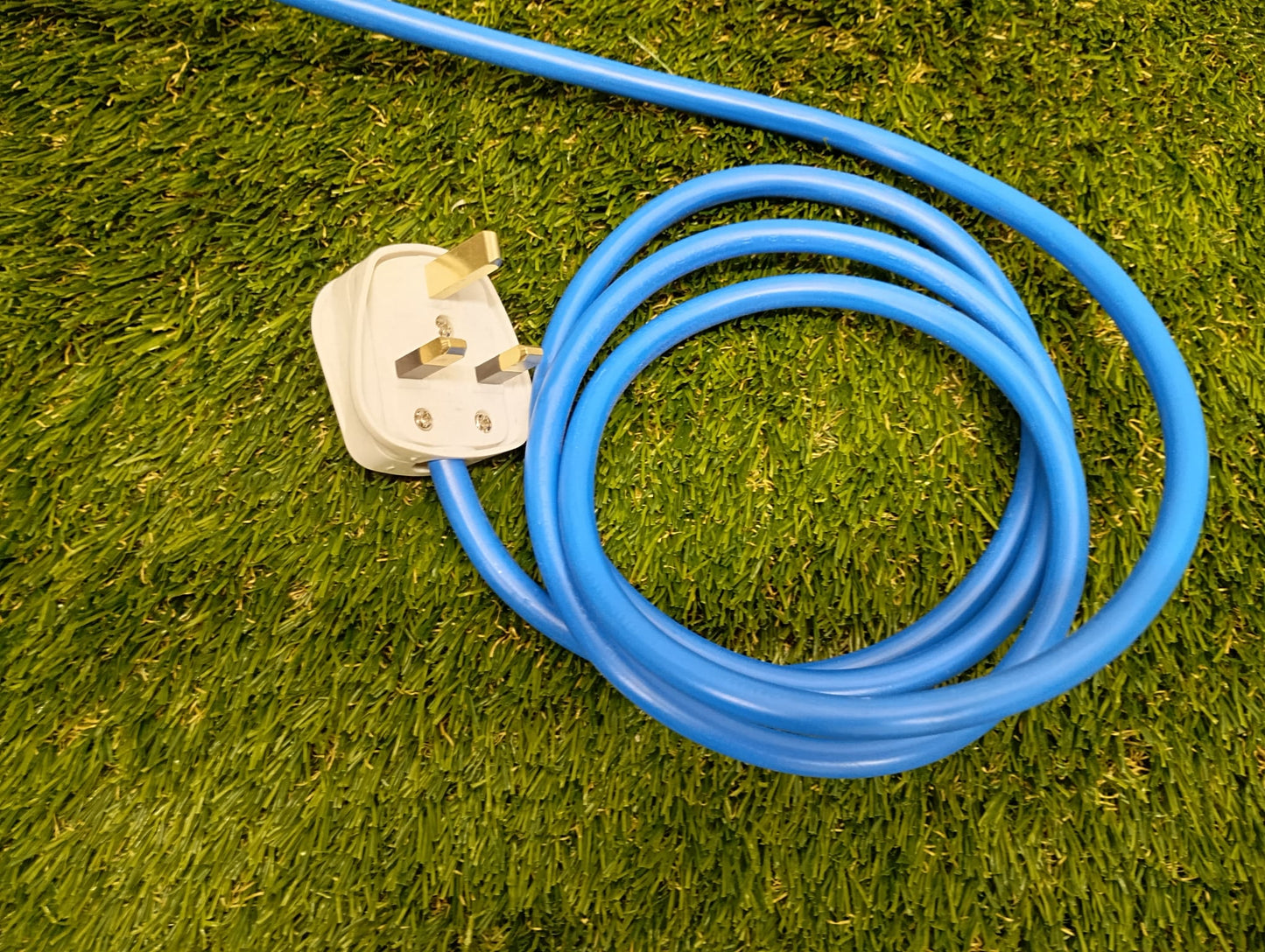 Coiled blue garden hose with a white plug on grass
