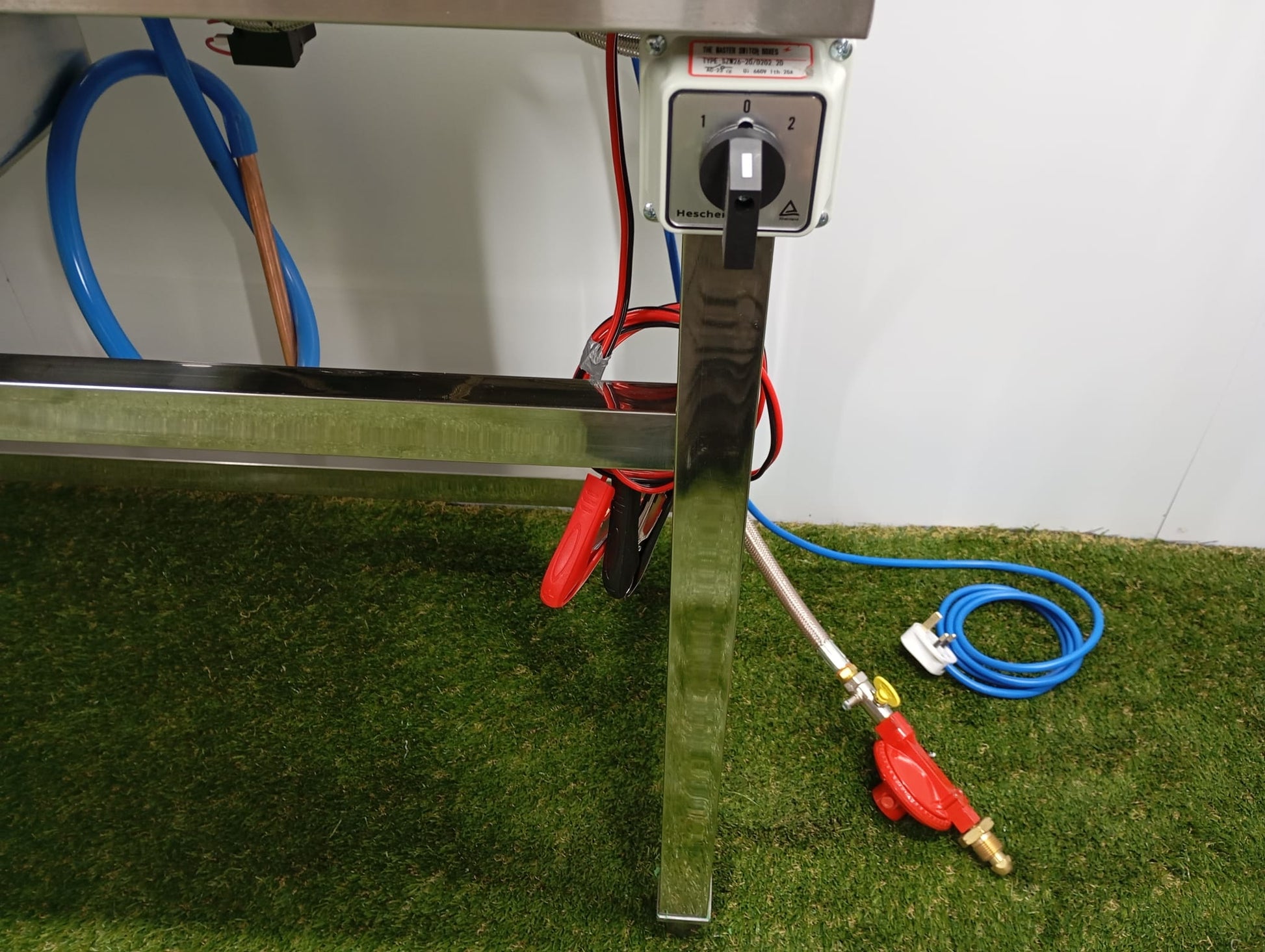 Metallic surface with hoses and a nozzle on a grassy background