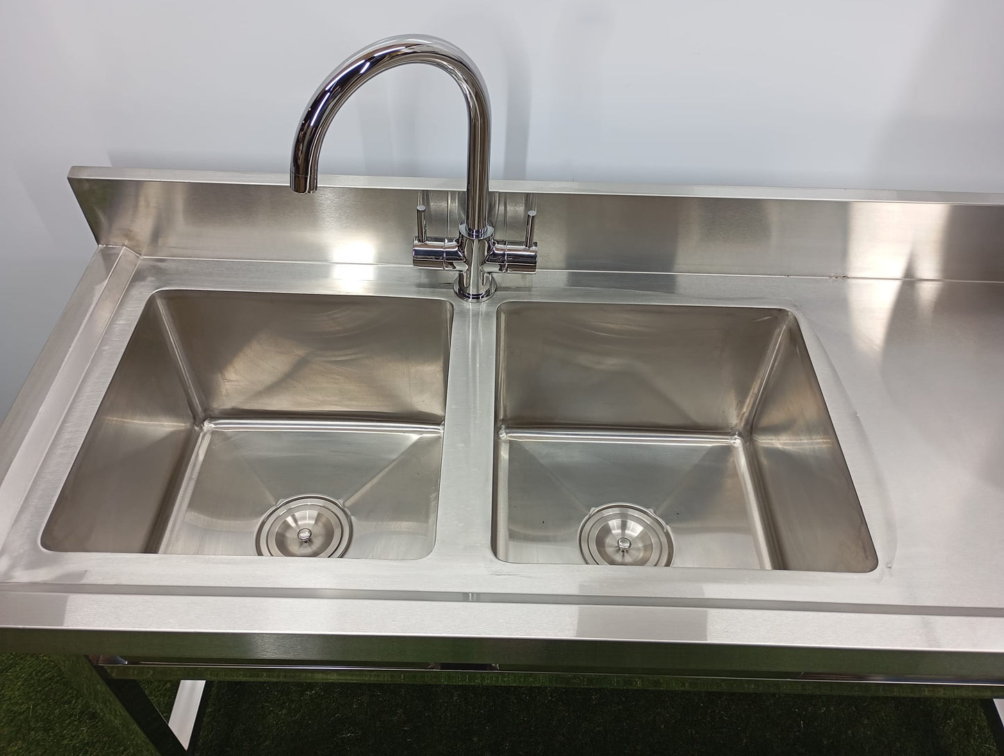 Stainless steel kitchen sink with faucet on a white background