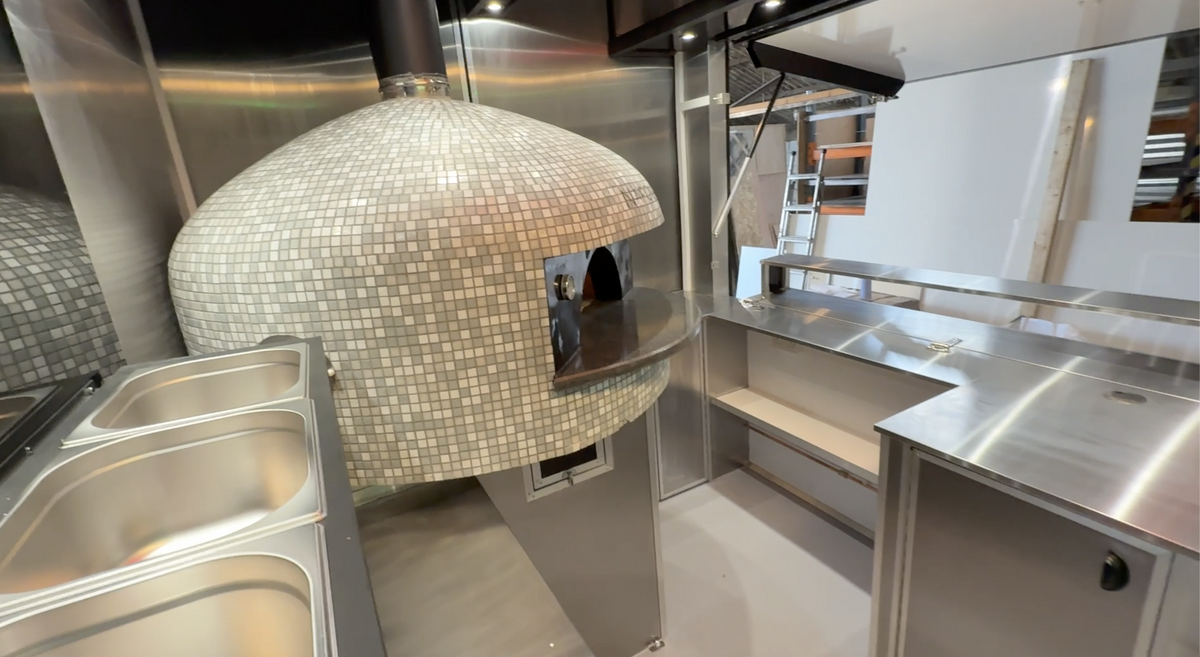 Commercial kitchen with a large pizza oven made of mosaic tiles.