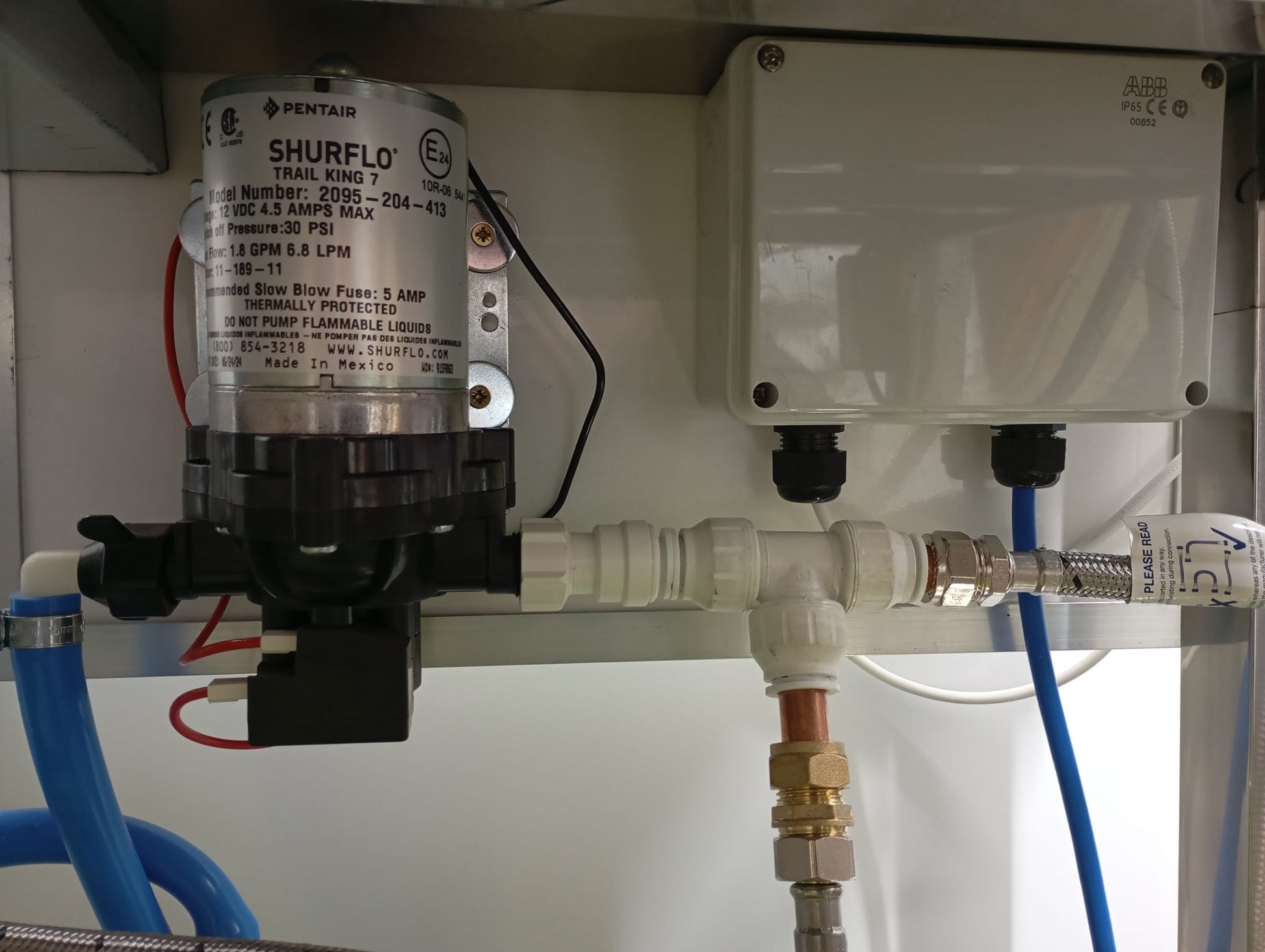 Shurflo pump with piping and connectors on a white background