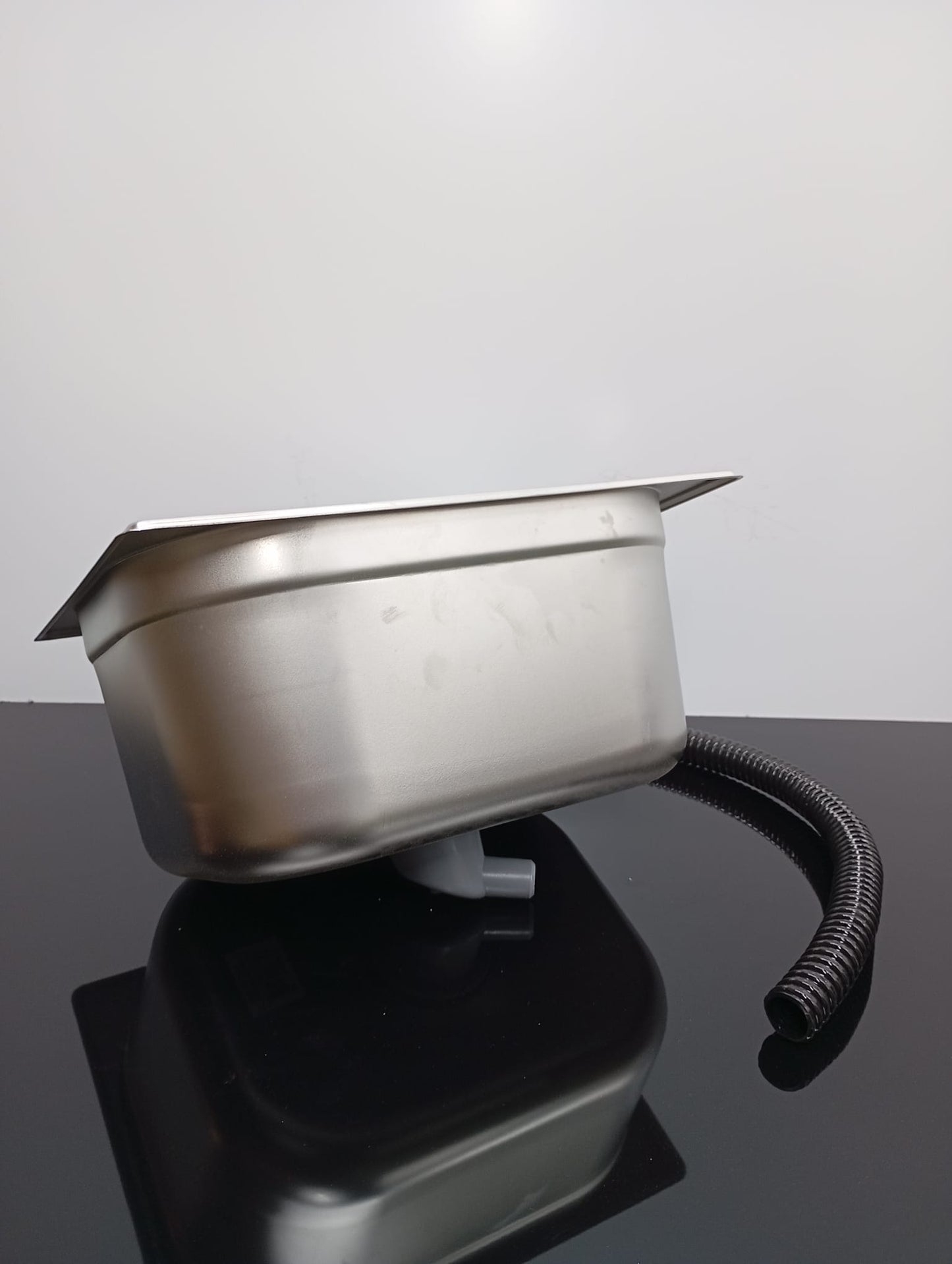 Metallic basin with a hose on a reflective surface