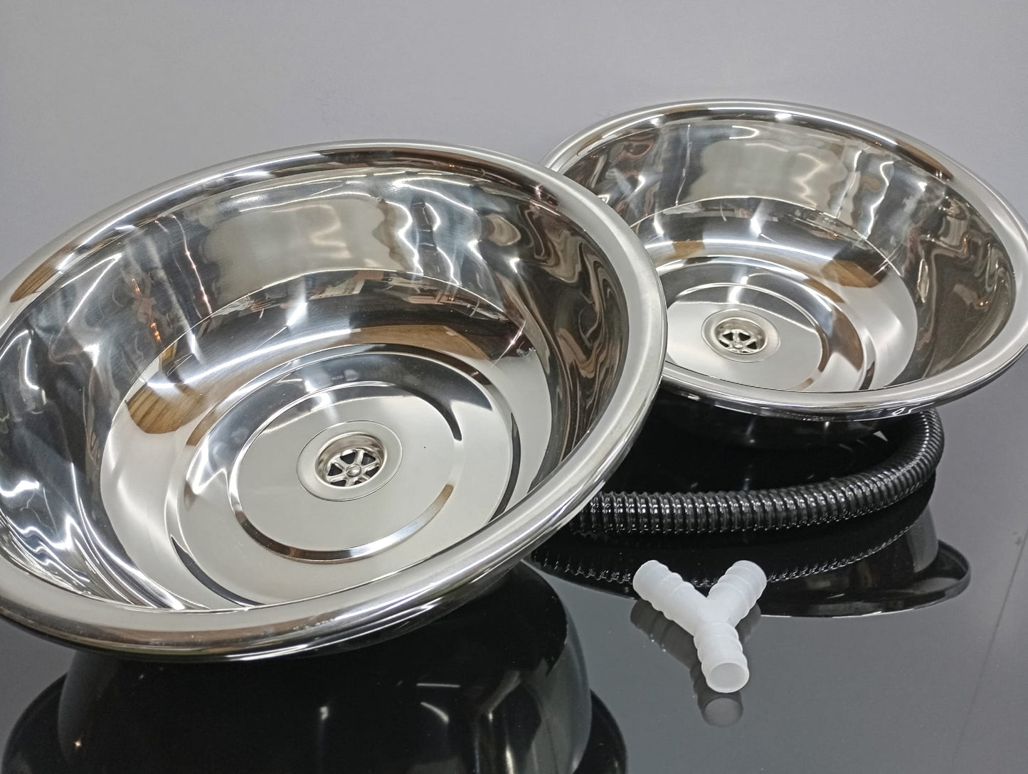 Two stainless steel bowls with a flexible hose on a reflective surface.